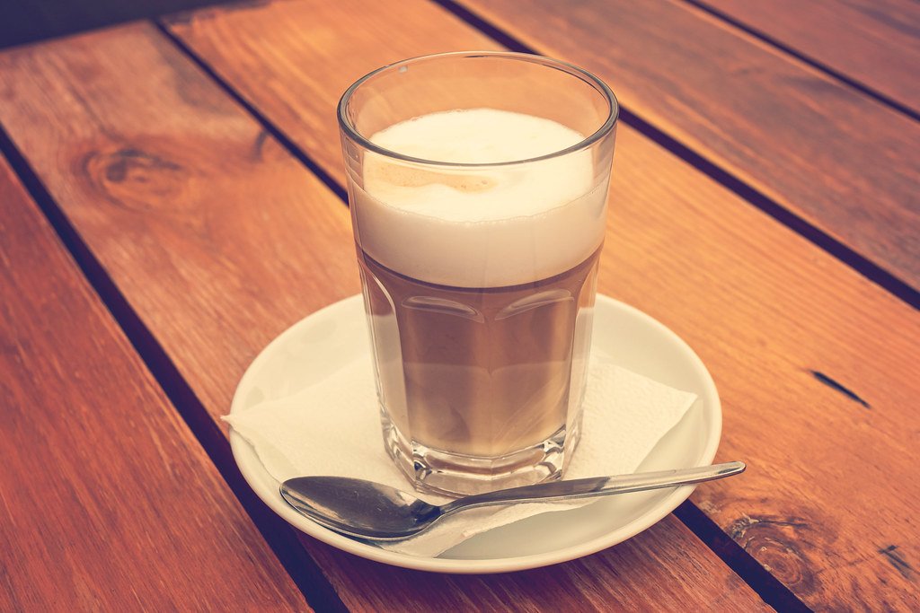 Café con leche texturizada servido sobre mesa de madera
