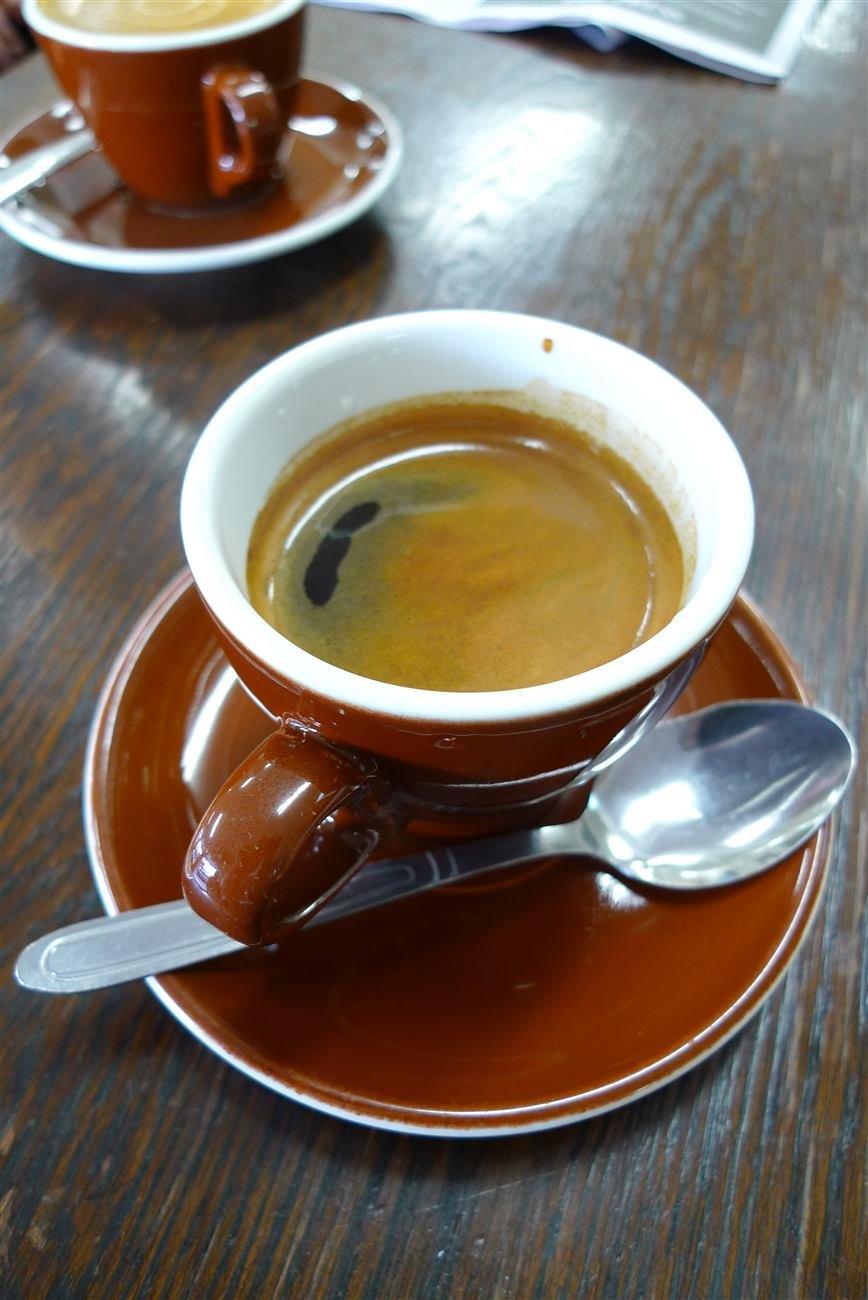 Café espresso servido en taza sobre mesa de madera